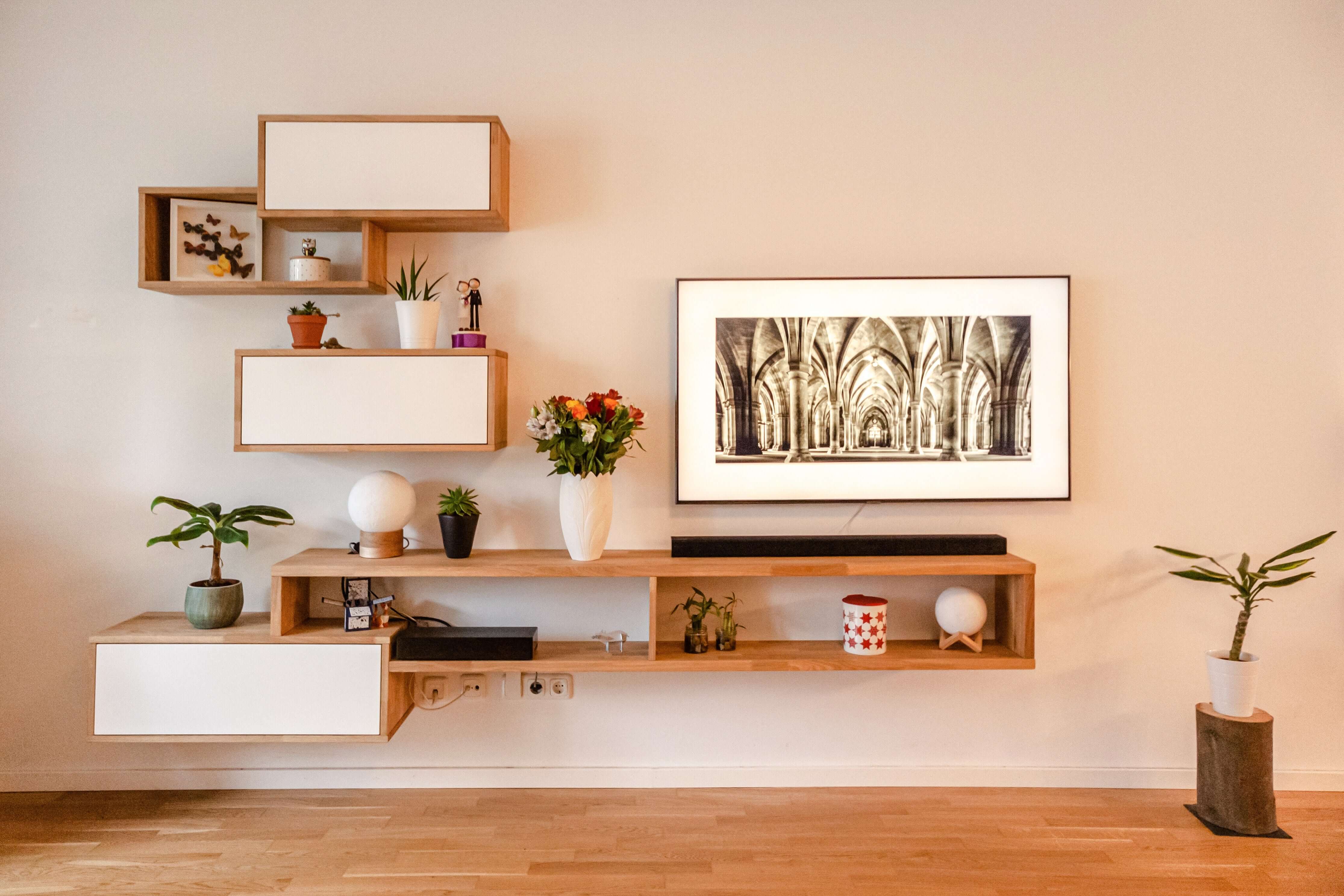 Étagères en bois massif installées sur un mur avec des plantes et une photo encadrée.