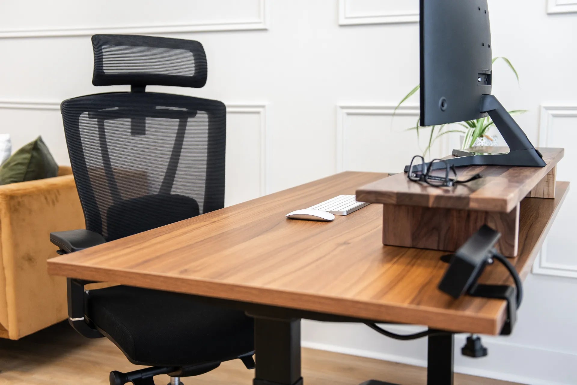 Close view of a black Burotic ergonomic chair with a mesh back beside a walnut desk