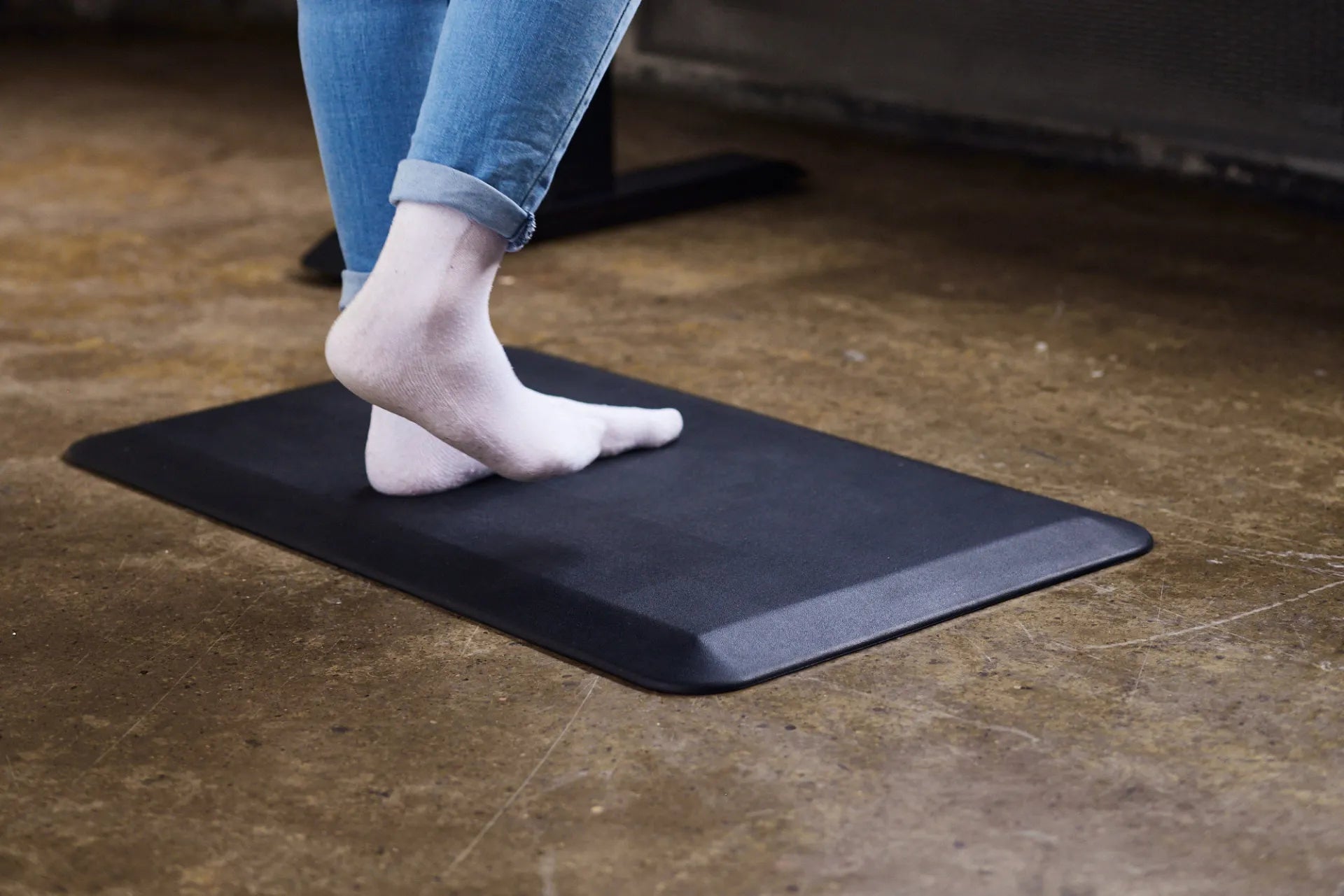 Person standing on a black Burotic anti-fatigue mat on a hard floor