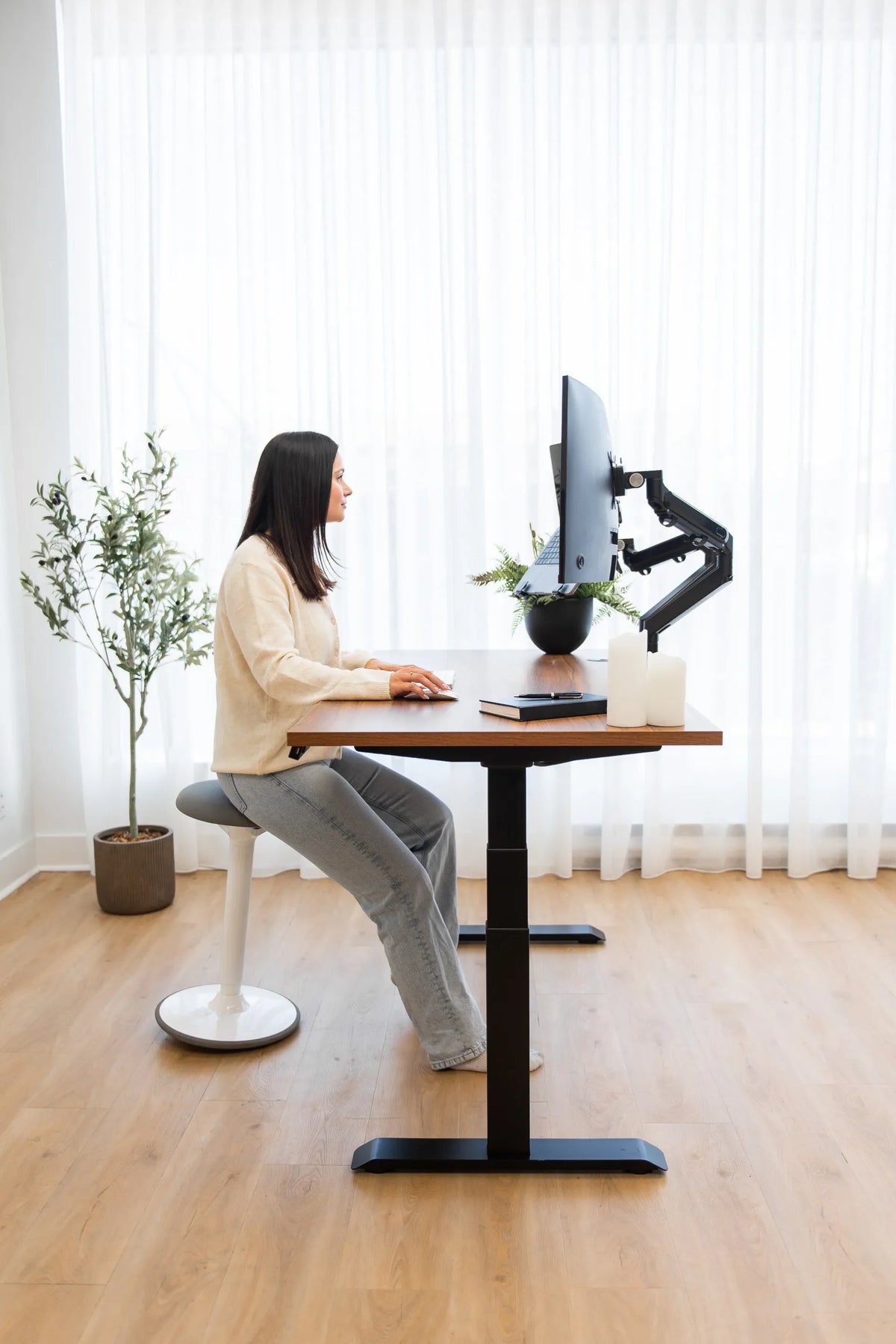 Side profile of a woman seated at an adjustable desk with feet supported on the floor