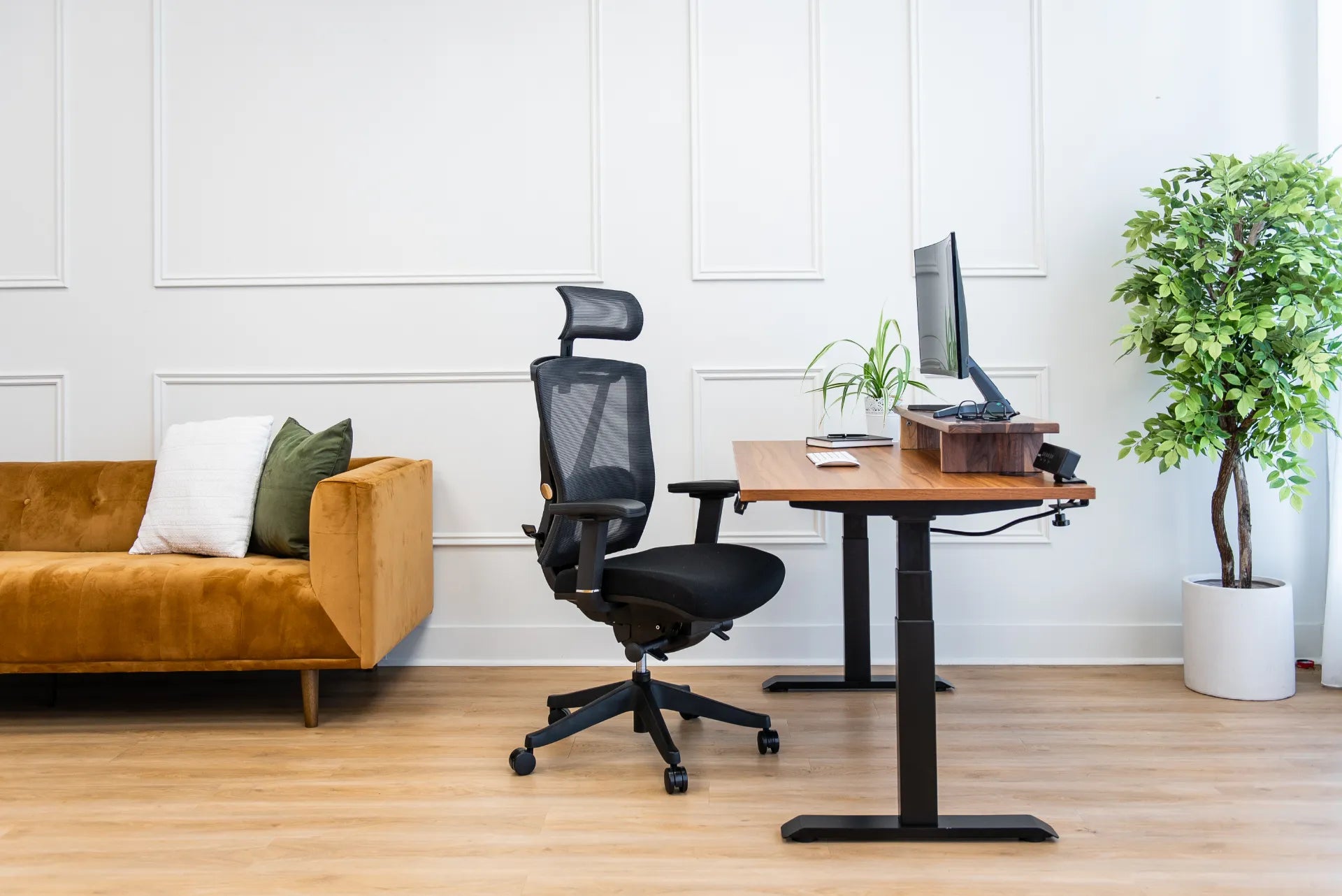 Black Burotic ergonomic mesh chair beside a walnut adjustable desk in a bright home office