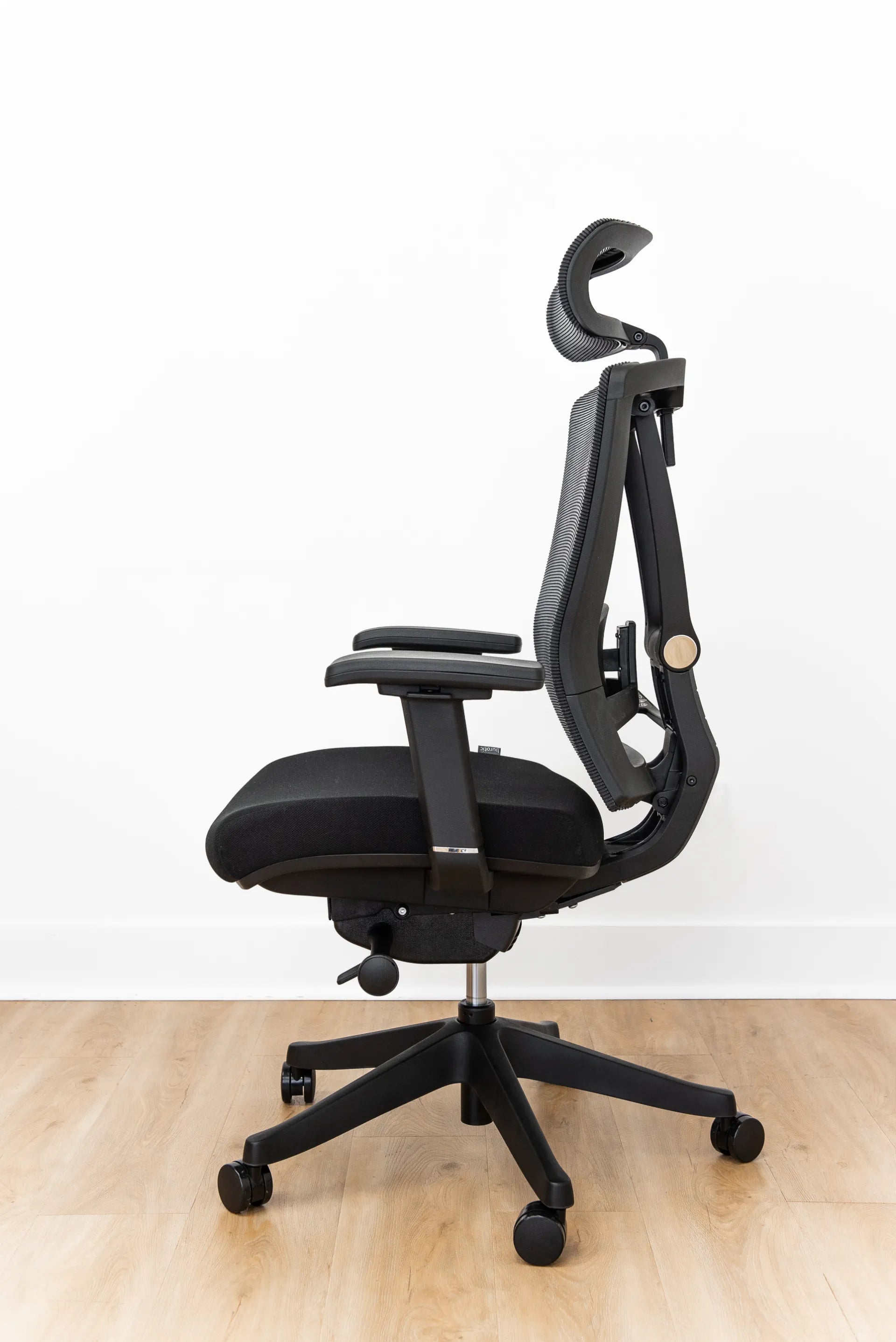 Side view of a black Burotic ergonomic chair showing the seat, gas lift, five-point base and casters