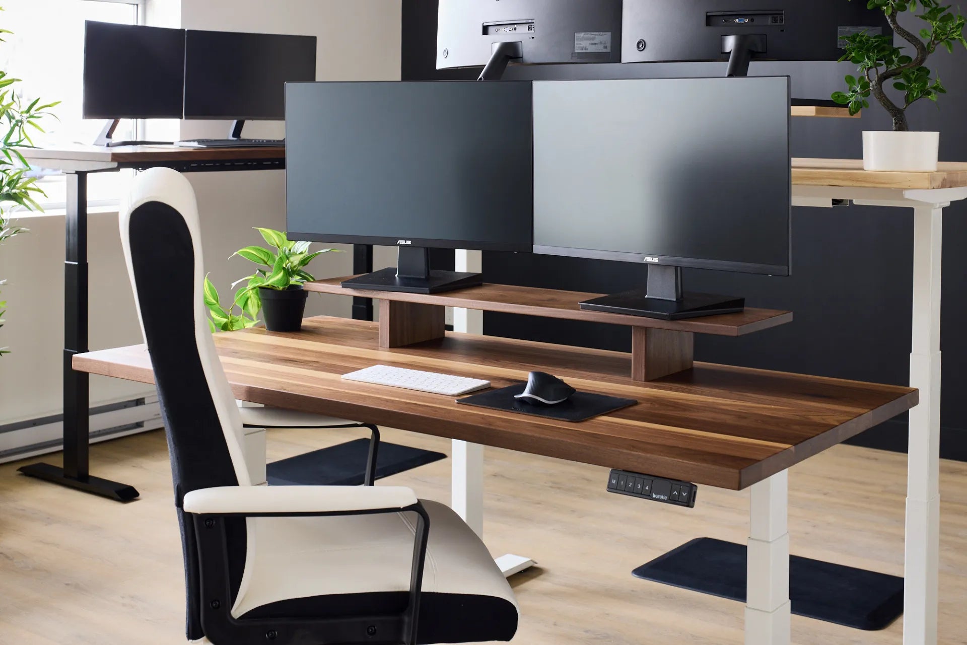 Two monitors arranged on a wood desk shelf in a Burotic showroom workspace