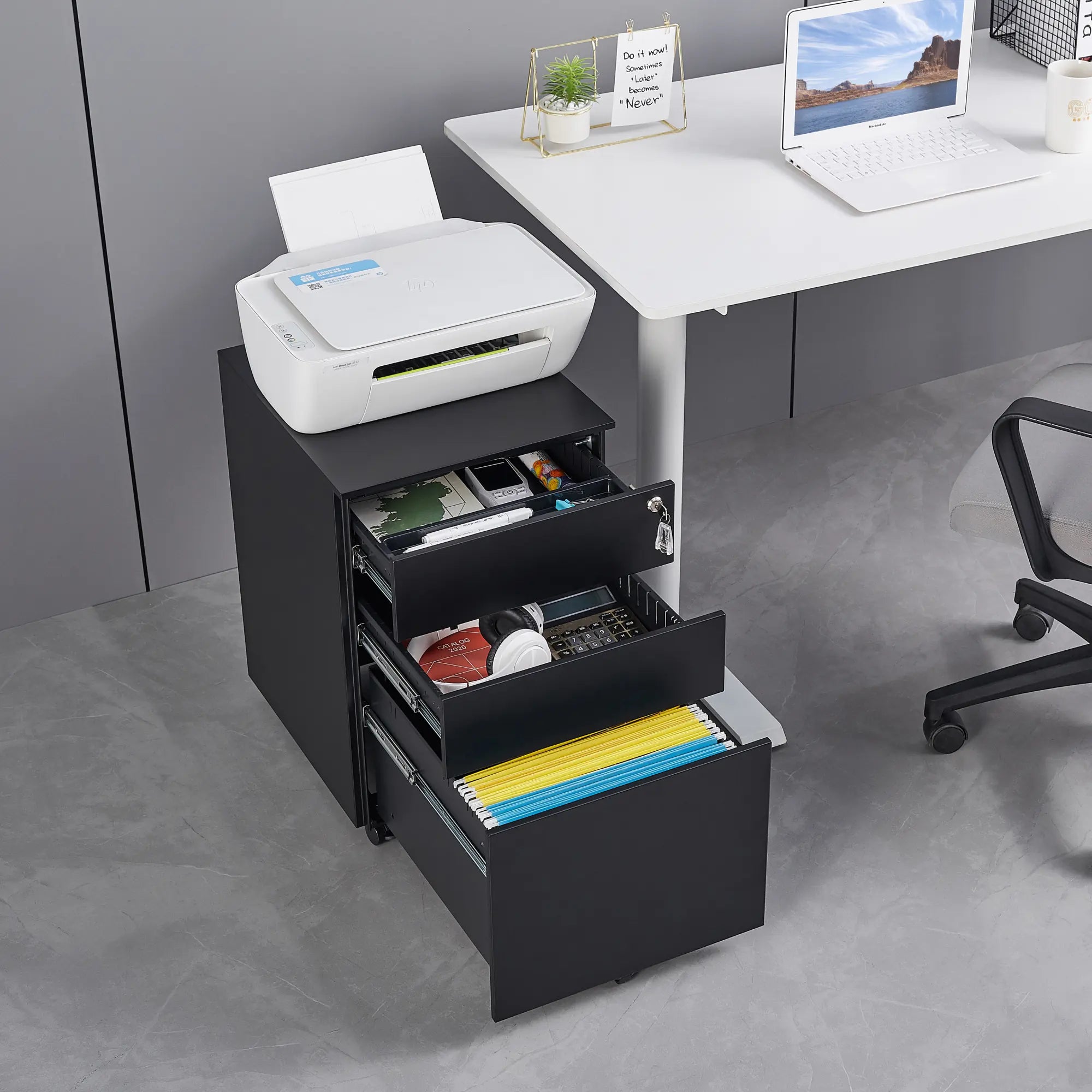Black office drawer unit with a printer on top, next to a white desk with a laptop.